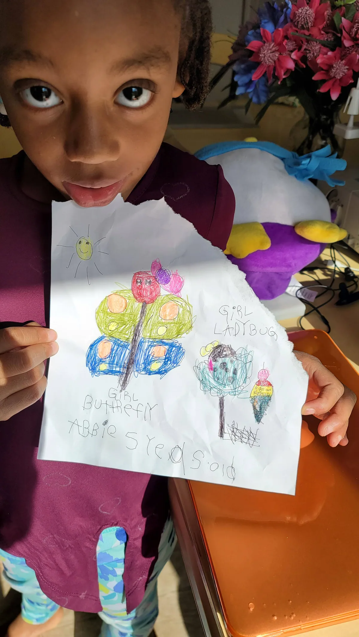 Abbie at five, holding her crayon drawing of "Girl Butterfly" and "Girl Ladybug"