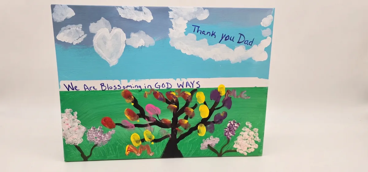 Acrylic painting of a tree with finger-painted leaves and the words "We are blossoming in GOD ways"