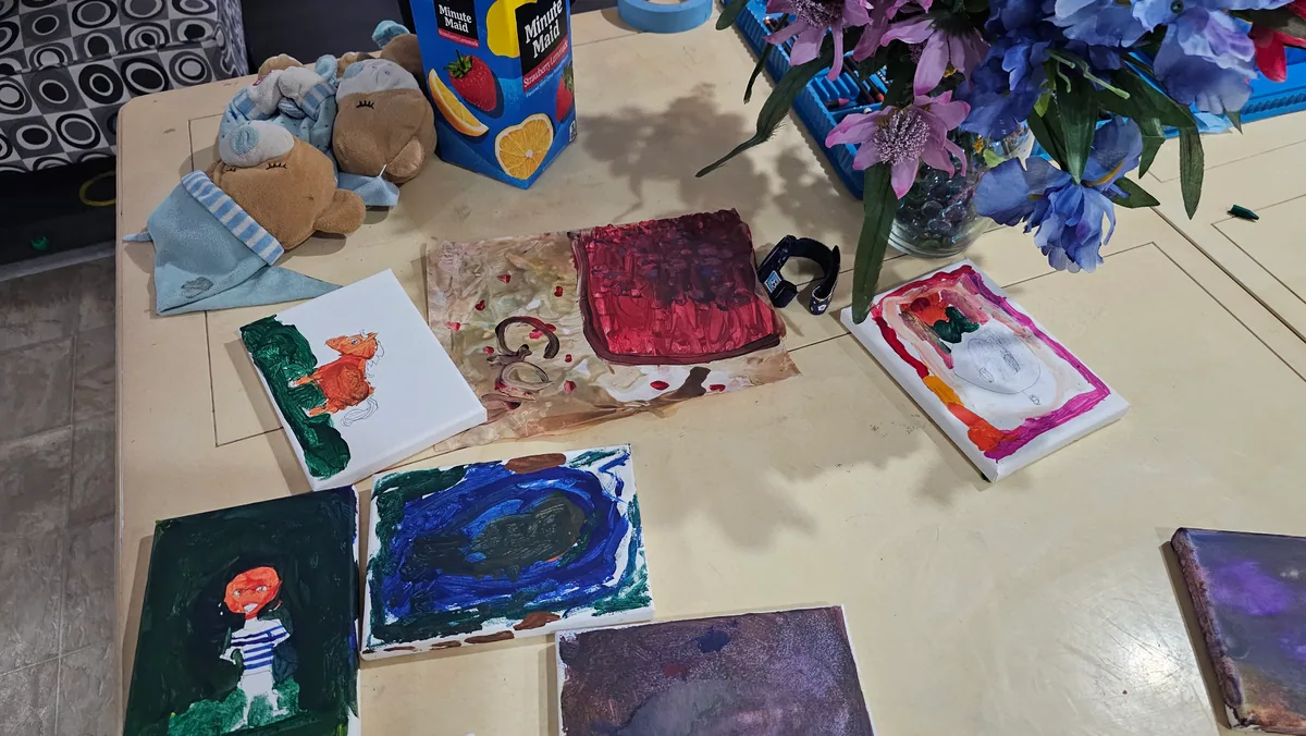 Multiple small canvases painted by the children, arranged on the studio table