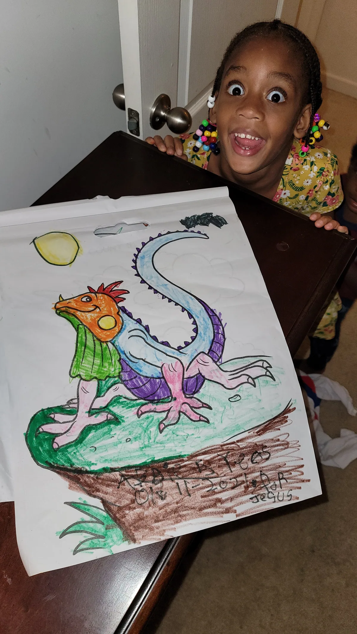 A beaming child showing off her crayon drawing of a dragon in a forest