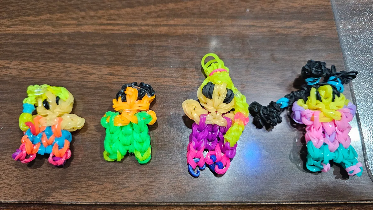 Four loom-band figures in rainbow colours — kid-made, sold as charms