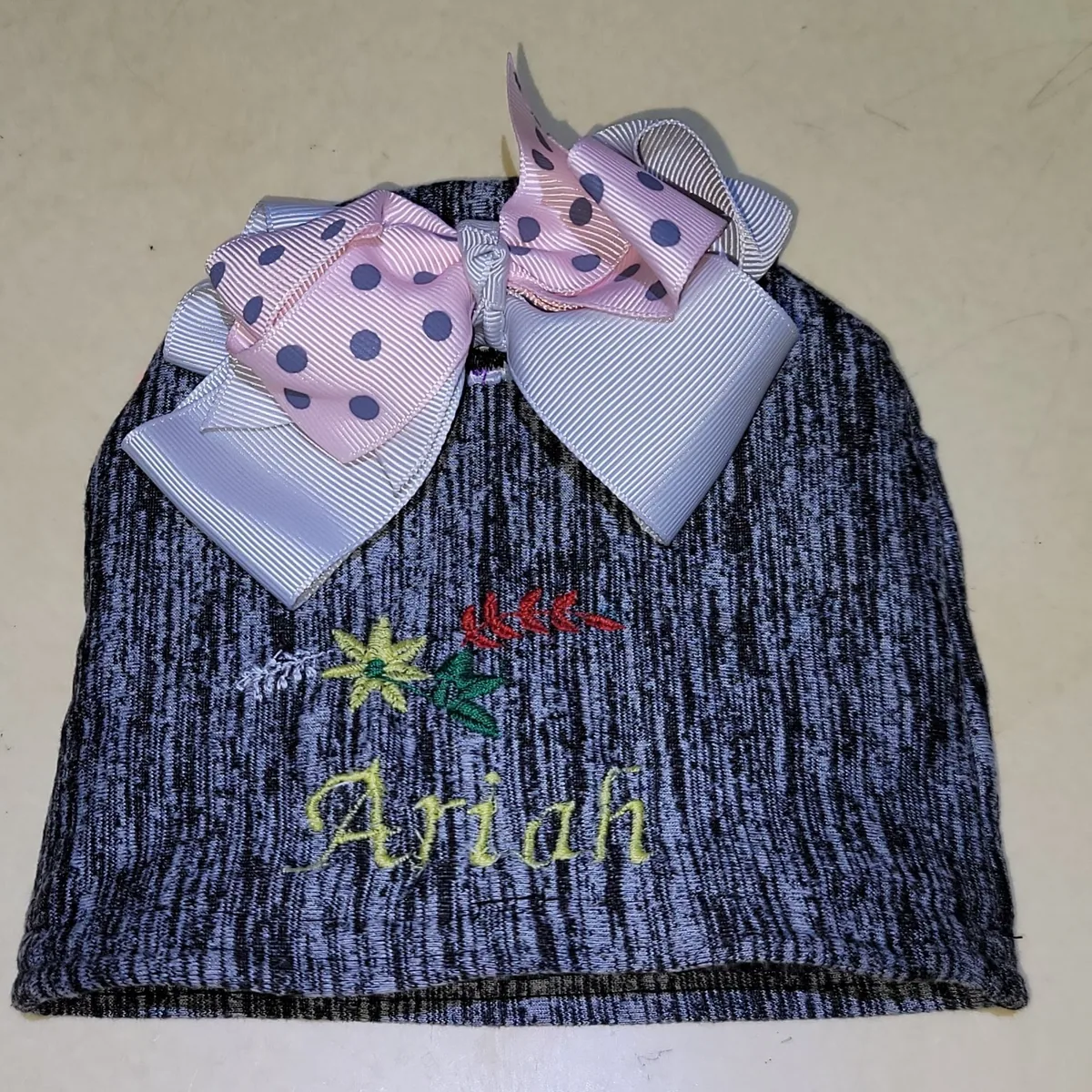 Heather-grey baby knit hat with embroidered "Ariah" and pastel polka-dot ribbon bow