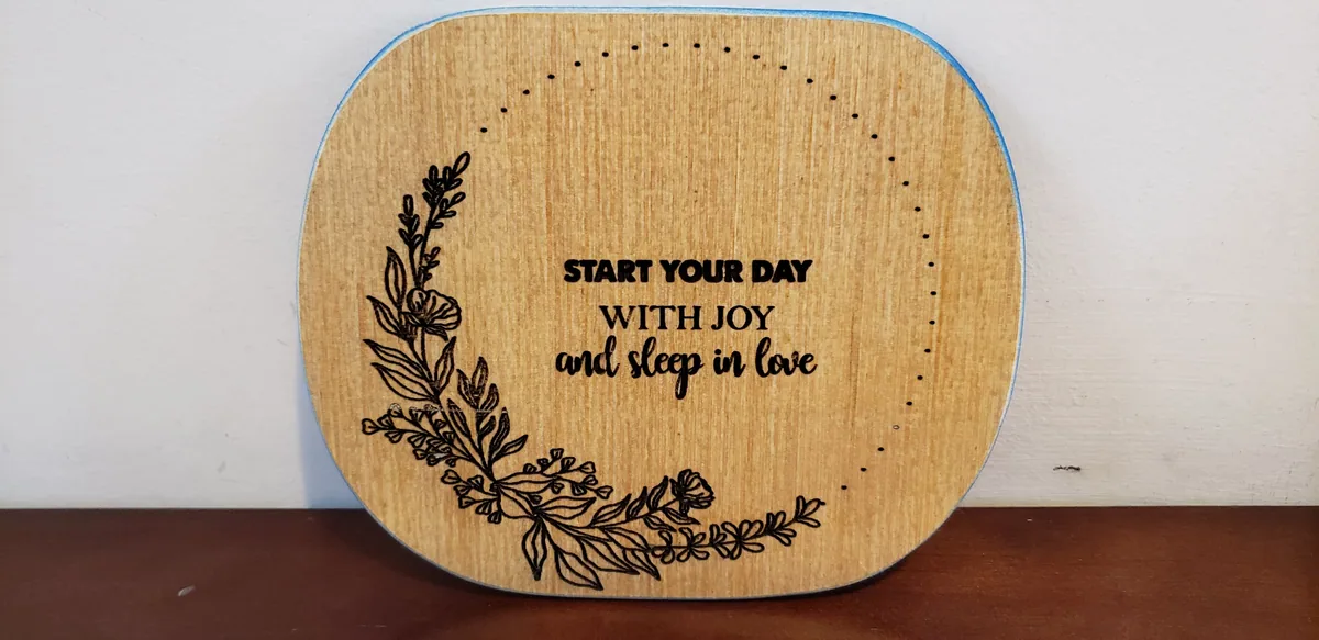 Laser-engraved wood plaque with botanical wreath and the words "Start your day with joy and sleep in love"